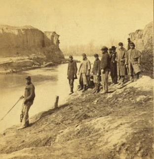 Dutch Gap canal and group of soldiers. Taken after the bank was blown out. On the extreme end a portion of the bank remains, which forms a profile, which the soldiers call Jeff. Davis. 1861-1865