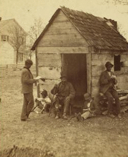 Uncle Abe's schoolhouse and scholars. [Man in a top hat in front of a shack with several boys with books.] 1868?-1900?