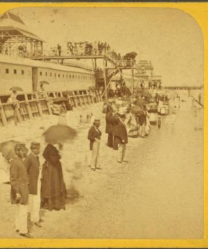 [People on the beach in front of the Plank Walk, some with umbrellas.] 1868?-1880?