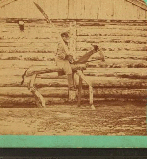 "Punishment Horse Bridger" [showing soldier on wooden horse holding oversized wooden sword over his shoulder in front of log building]. 1865?-1897