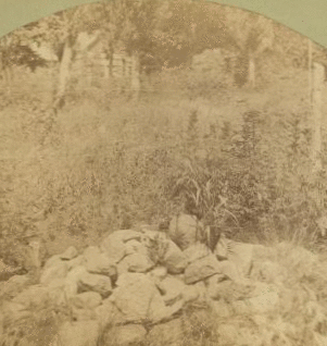 The stone pile that marks the grave of the Gardner family, massacared in 1857 and the cabin in the background. 1865?-1885? 1883