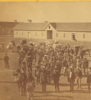 Taken at Fort Wingate, Dec. 11, 1871 [a group of native Americans and Burros in front of a building.] 1870?-1908