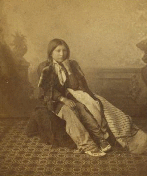 [Studio portrait of a young Native American woman in tradtional clothing.] 187- 1865?-1885?