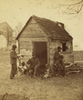 Uncle Abe's schoolhouse and scholars. [Man in a top hat in front of a shack with several boys with books.] 1868?-1900?