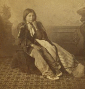 [Studio portrait of a young Native American woman in tradtional clothing.] 187- 1865?-1885?