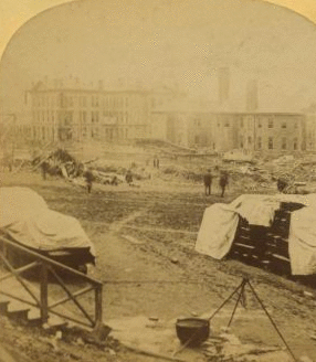 A view taken from the rear of the P. R. R. depot. In the middle ground are seen the stores and offices of the Cambria Iron Co., and in the foreground are coffins and bodies just arrived from the morgues and ready for shipment. 1889