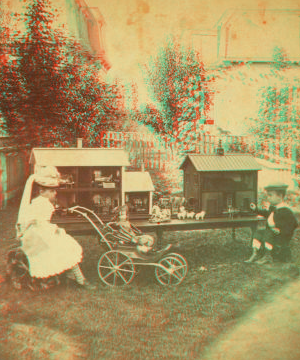 [A boy and girl sitting outside and playing with dollhouses, baby carriage and doll.] 1865?-1885?