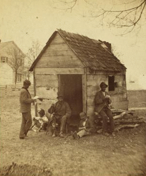 Uncle Abe's schoolhouse and scholars. [Man in a top hat in front of a shack with several boys with books.] 1868?-1900?