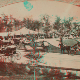 Music day in the park. [Crowd and coaches gather around music stand and tents.] 1860?-1905?