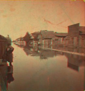 [Wooden houses along a flooded Main street.] 1868?-1901?