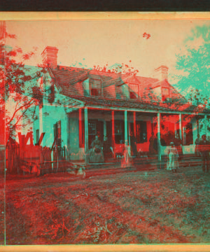 [View of a small house with family on porch.] 1865?-1905?