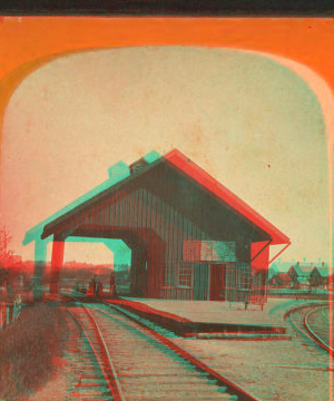 [View of railroad depot with shed roof over tracks.] 1865?-1880?