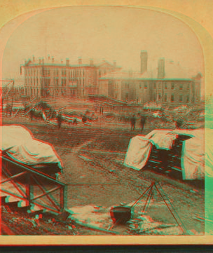 A view taken from the rear of the P. R. R. depot. In the middle ground are seen the stores and offices of the Cambria Iron Co., and in the foreground are coffins and bodies just arrived from the morgues and ready for shipment. 1889