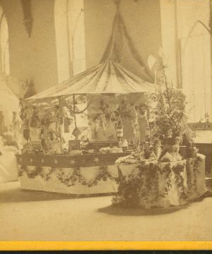 [Interior view of a fair or church bazaar showing tables draped with flowers and arranged with items.] 1865?-1900? [ca. 1880]