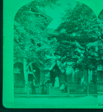 [Festooned brick building, with men and women posing at porch entrance, Wilkes-Barre, Pa.] 1860?-1900? 1878