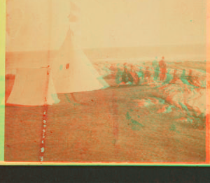 [Group of people sitting on rocks, in front of a tent and a tipi.] 1860?-1869?