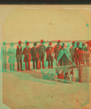 [Portrait of two women (with a wheelbarrow and barrel) and nine men standing on the beach.] 1869?-1880?