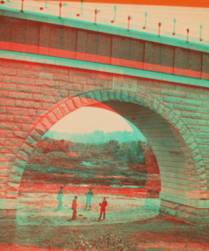 [View of two people standing under completed arch.] 1876?-1878?