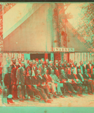 [Group of men formally posed in front of large tent with sign that reads "Warren".] 1865?-1880?