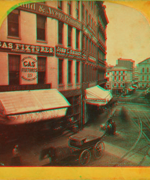 [View of unidentified street with commerical buildings, trolley tracks, and buggies.] 1859?-1901?