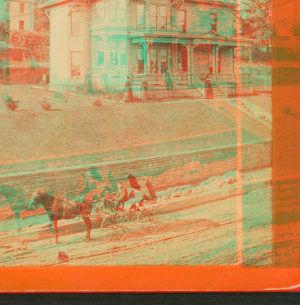 [Three-story frame house on terraced yard; people pose on porch; young man holds reins in one-horse carriage. Retaining wall and street under construction.] 1860?-1900?