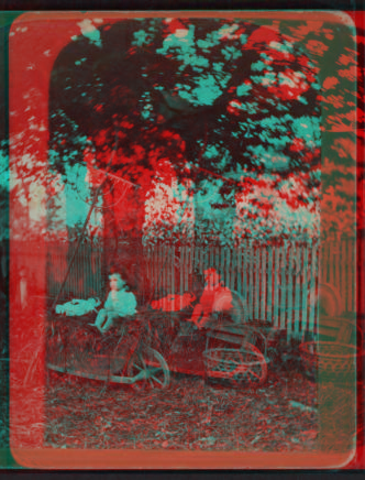 [A child sitting in a wheelbarrow with her doll, ax sharpener, rake, basket and watering can nearby.] [ca. 1880] 1870?-1890?