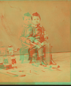 Little boy with a block of wood, carving tools and a doll. 1868?-1885?