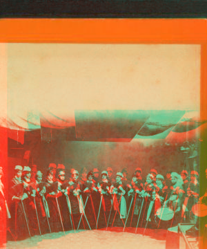 [Studio view of a group of women holding brooms(?) and 1 woman with a drum.] 1865?-1885?