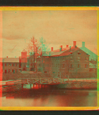 [View of unidentified industrial buildings on a river.] 