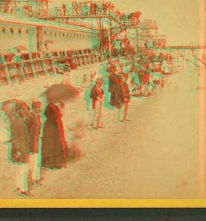 [People on the beach in front of the Plank Walk, some with umbrellas.] 1868?-1880?
