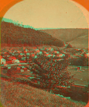 [Small village at foot of hill; small tree and railroad car in foreground.] 1860?-1915?