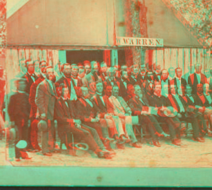 [Group of men formally posed in front of large tent with sign that reads "Warren".] 1865?-1880?