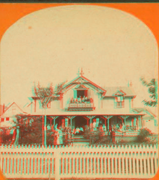 [Cottage with white picket fence, people in front and on the balcony.] 1865?-1885?