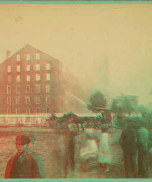 [View of a fire in large industrial building with men spraying water.] 1865?-1903 [187-]