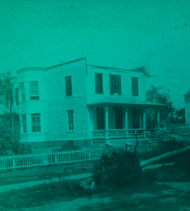 [View of a downed tree in front of a house with fence.] 1878