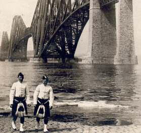 Highlanders in native costume at the great Forth Bridge, one and one-half miles long, spanning the Firth of Forth, Queensferry, Scotland