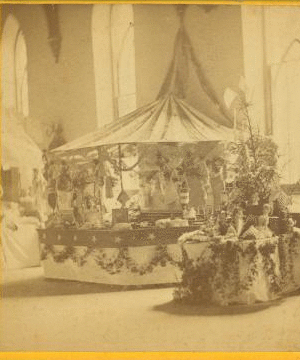 [Interior view of a fair or church bazaar showing tables draped with flowers and arranged with items.] 1865?-1900? [ca. 1880]