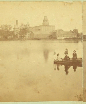 [Children in a boat in front of unidentified mill or factory building.] 1865?-1885?